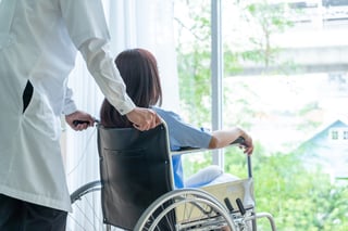 Healthcare worker supporting wheelchair patient